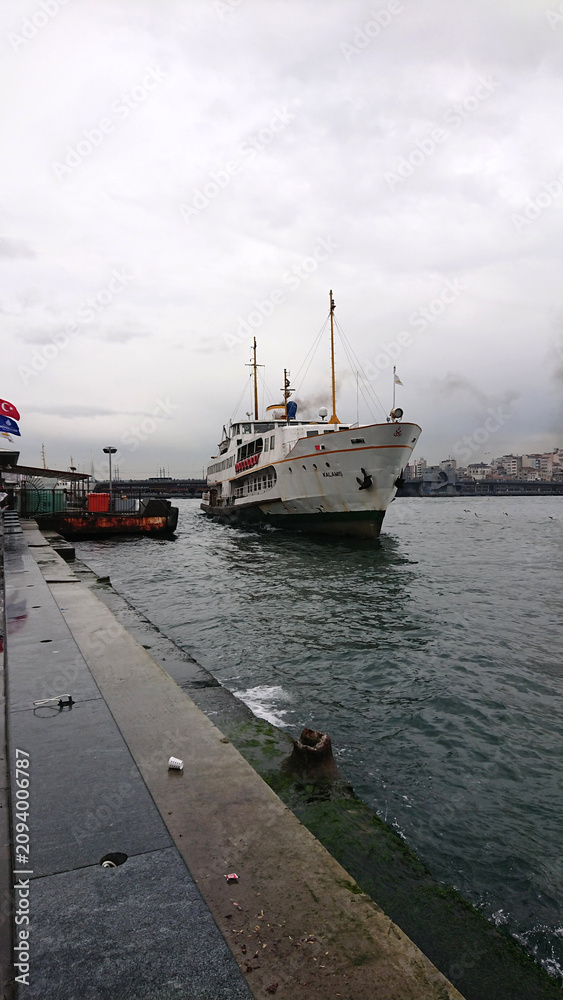 Fototapeta premium Traditional Istanbul ferry arriving at Karakoy pier on a cloudy day