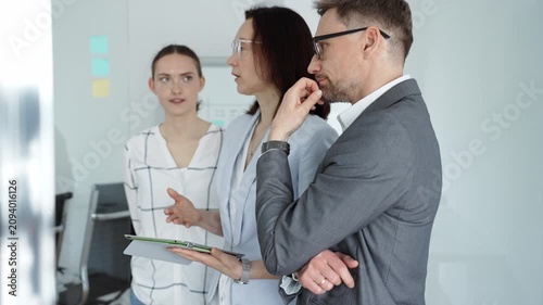 Business team collaborating on strategy, brainstorming ideas with post it notes on a glass board during an office meeting, planning effective project development