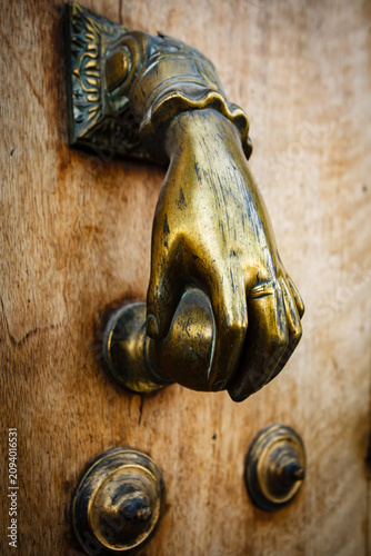 Принти на полотні Closeup of a brass door knocker shaped like a hand turning a door knob