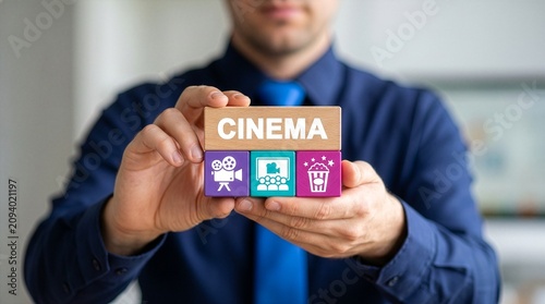 Business person holding colored blocks sees the word CINEMA. Cinema Business Service Web Technology Concept. Movie theater. New