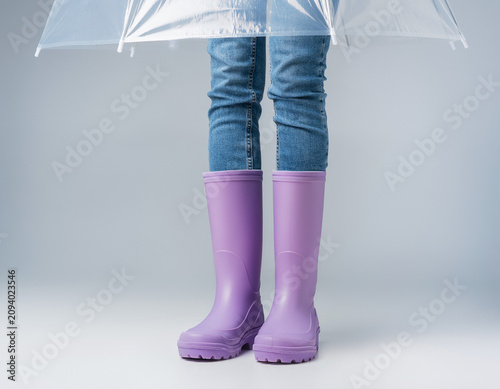 Studio Portrait of Person Wearing Rain Boots and Poncho on White Surface from Top Down View