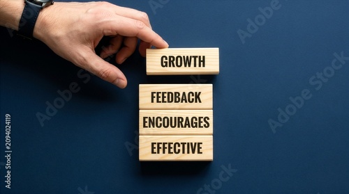 Feedback symbol. Wooden blocks with words Effective Feedback encourages growth. Businessman hand. Beautiful deep blue background. Business and Effective Feedback. New concept