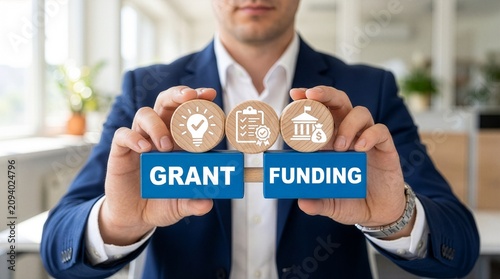 Man holding colorful blocks with icons and inscription GRANT FUNDING. Concept of grants and funding. New concept