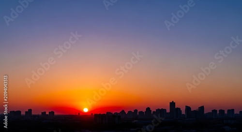 Cityscape silhouette against vibrant orange and purple sunset sky