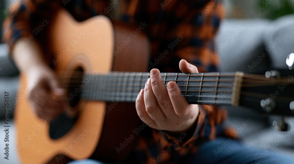 Obraz premium Close-up of a person playing an acoustic guitar, focusing on hand positions and strings