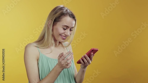 An Excited Woman Embracing Her Smartphone While Posing Against a Bright Yellow Background