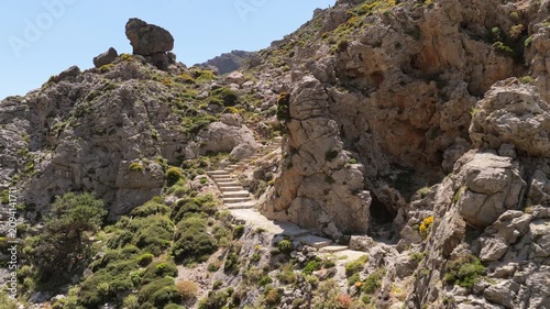 Aerial drone view of ancient stone steps winding up a rugged rocky hillside in a mountain gorge, Kourtaliotiko Gorge, Greece