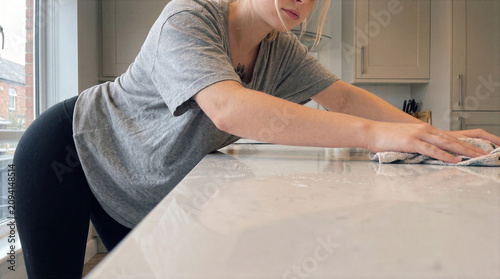 Young Woman Wiping Kitchen Countertop During Home Cleaning