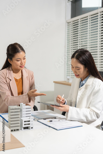 Real estate broker agent presenting and consult to customer to decision making sign insurance form agreement, home model, concerning mortgage loan offer in office