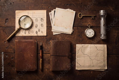 Detective desk photo with notebook magnifier fingerprints vintage watch and map