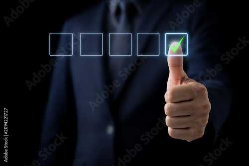 Businessman giving thumbs up with five star rating interface on dark background