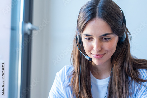 Konstfotografi Smiling customer service representative wearing a headset working remotely at a