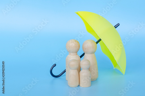 Wooden figures with a yellow umbrella representing security and insurance with customizable space for text.