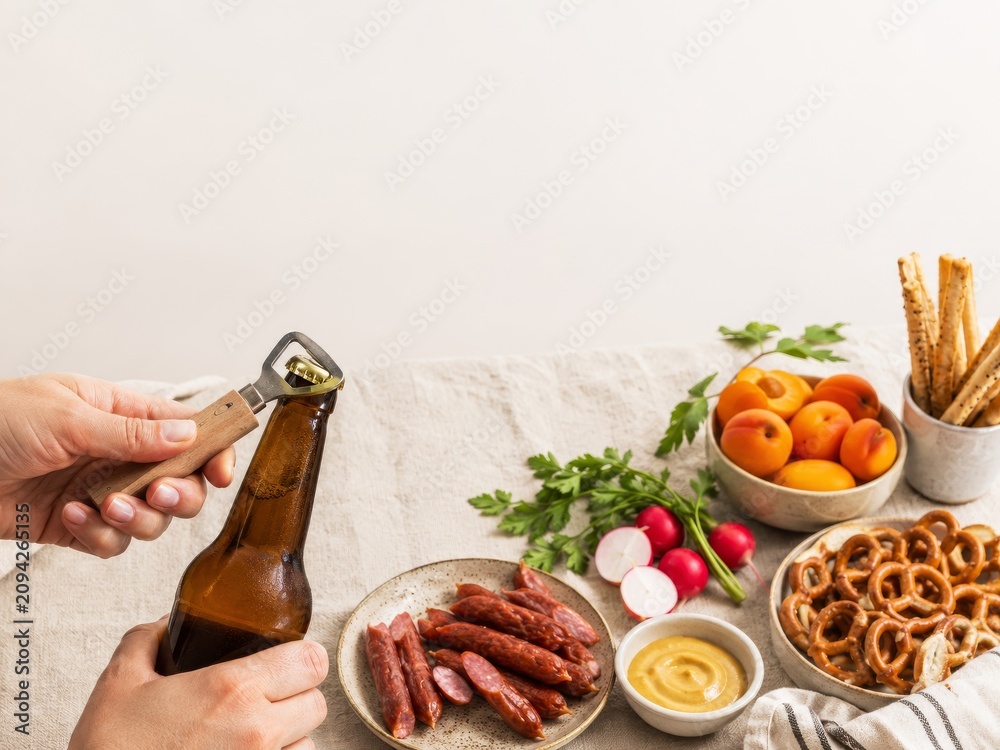 Fototapeta premium Cerveza y aperitivos en una mesa con salchichas, pretzels y fruta fresca