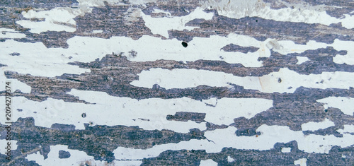 Fotografía Worn white paint surface peeling severely, revealing the underlying blackish-dar