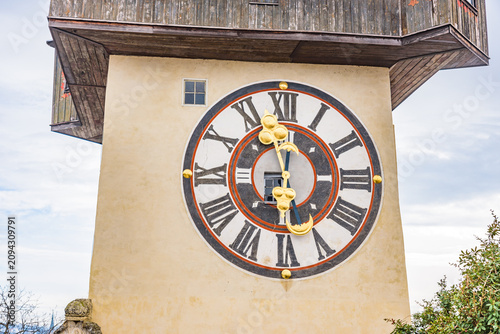 A closeup view of the iconic Graz Clock Tower (Grazer Uhrturm) with its unique historic clock face on the Schlossberg hill, a UNESCO World Heritage Site in Graz.