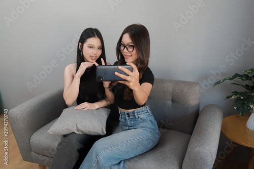 Asian Women Recording Selfie Video Together Using Smartphone Indoors