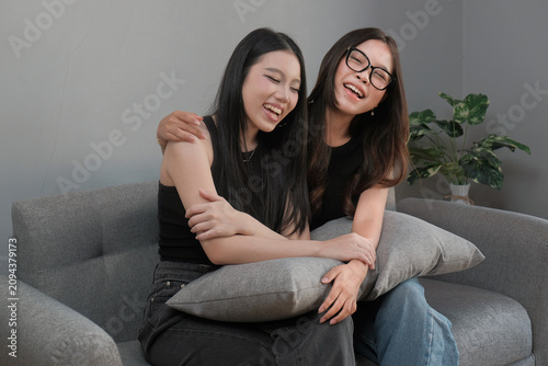 Cheerful Young Asian Women Laughing Together in a Cozy Living Room