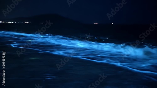 Dramatic Bioluminescent Waves Splashing on Dark Shore at Night with Glowing Blue Water