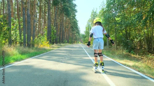 Girl is roller skating by forest, enjoying an active hobby in the open air.
