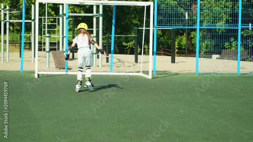 Little girl on roller skates in helmet at a park. Child in protective sportswear