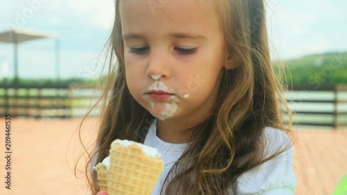 Little girl in the summer eating delicious ice cream. Child with ice-cream in the park. Childhood concept
