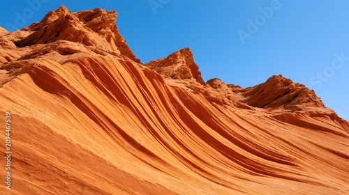 A dramatic view of layered orange sandstone formations sculpted by wind erosion under a clear blue sky
