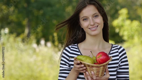 woman holding a basket of fruits and eating apple