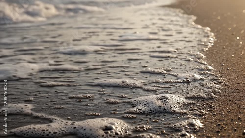 Ocean Waves Lapping Onto Sandy Beach At Golden Hour Close Up