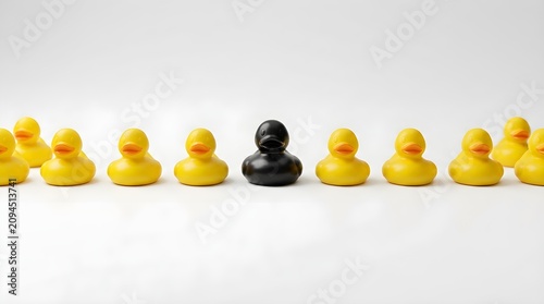 Rubber ducks arranged in a line show one black toy standing out among many yellows.