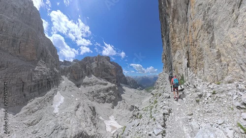 Rear view of two hikers traversing the exposed Via Ferrata Bocchette Centrali overlooking Brenta Valley