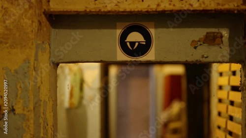 Signboard With Protective Helmet Icon At Entrance. Empty Old Abandoned Bomb Shelter. Ruins Cold War Underground Bunker 