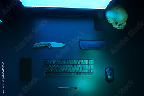 Gamer or hacker workspace flat lay with neon light and skull.