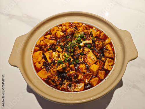 A steaming clay pot of authentic Mapo tofu features soft bean curd cubes in a fiery, savory chili oil sauce