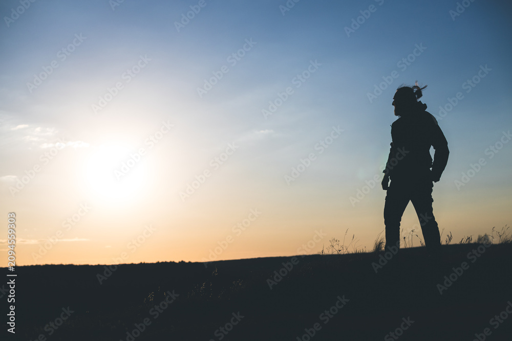 Fototapeta premium Confident Silhouette Standing Firm Against the Sunset Sky