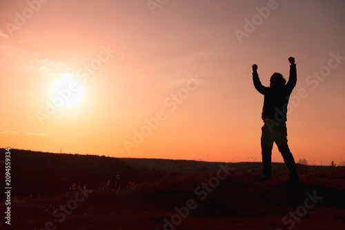 Bild auf Leinwand Jubilant Silhouette Celebrating with Arms Raised at Sunset