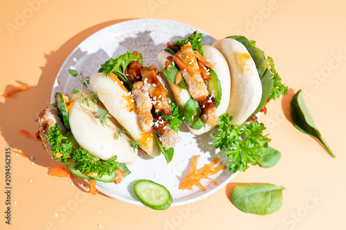 Asian-style bao buns stuffed with succulent teriyaki chicken, served on a colorful yellow surface.
