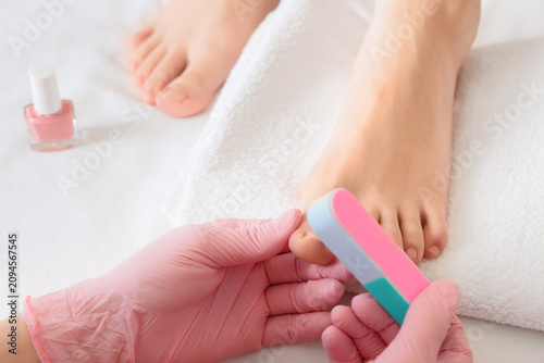 Pedicurist in pink gloves f...