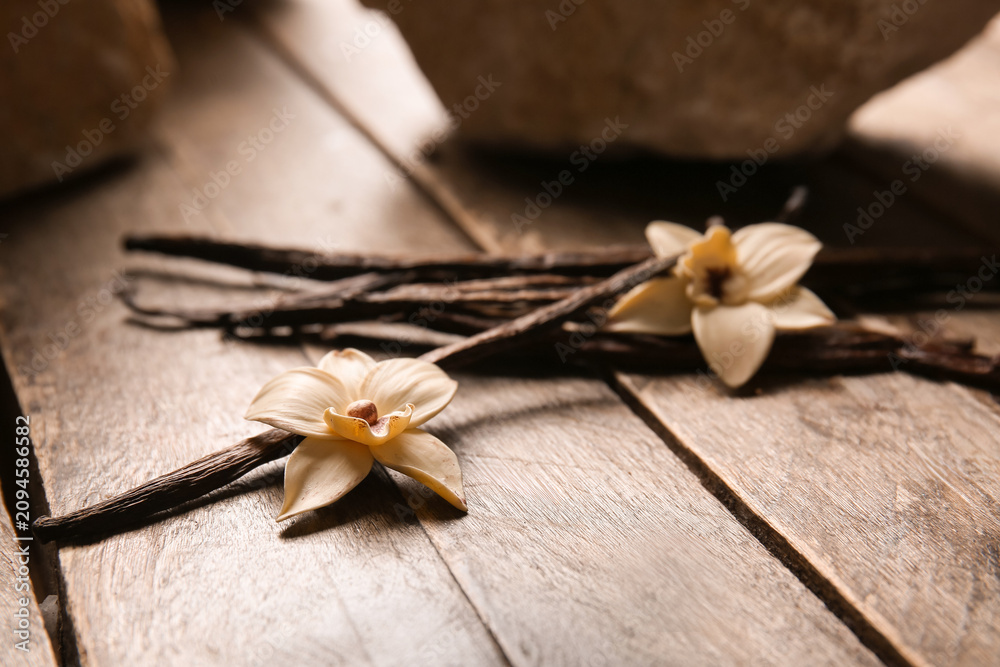 Fototapeta premium Dried vanilla sticks and flowers on wooden background, closeup