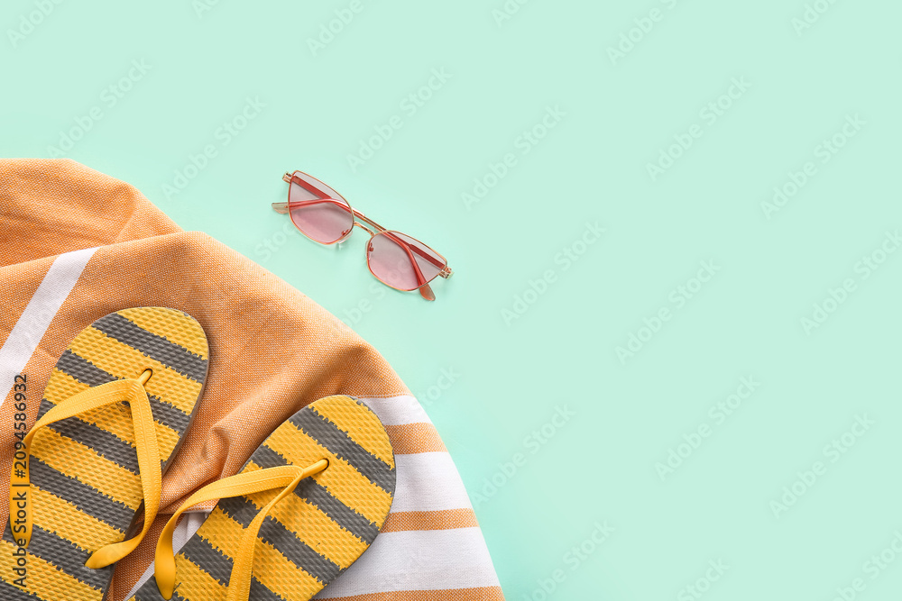 Obraz premium Flip-flops, beach towel and sunglasses on turquoise background, closeup
