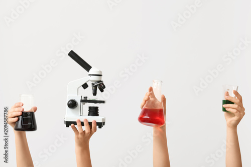 Female hands with modern microscope and laboratory glassware of samples on gr...
