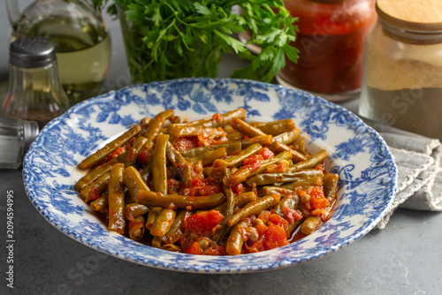 Traditional Turkish green beans stew cooked with tomatoes and olive oil on a ceramic plate