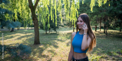 Teen girl smiling while talking on phone outdoors in a park
