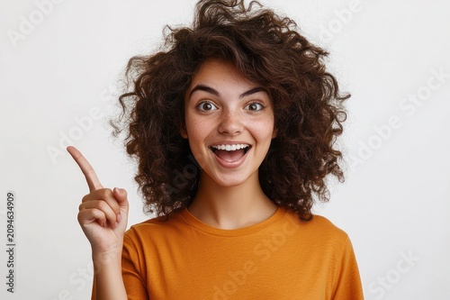 person with curly dark hair and blurred face in orange shirt pointing upward with index finger against plain white background, conveying a thoughtful idea and assertive gesture