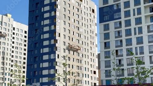Workers on scaffolding apply paint to the exterior of a modern apartment building, showcasing the ongoing construction in an urban environment