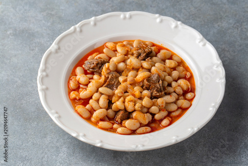 Traditional Turkish etli kuru fasulye white bean stew with meat on a white plate