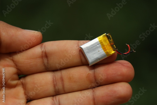 Small li-Po or known as lithium polymer battery with connection wires held in the finger