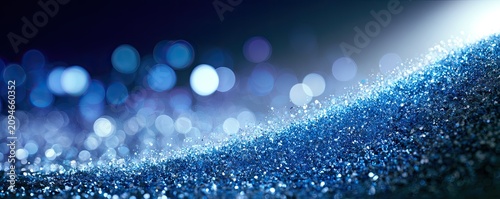Blue glitter forms a shimmering wave against a dark, bokeh-lit background