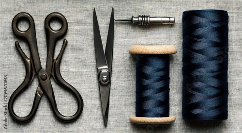 neat flat lay of two vintage scissors, a sharp dressmaker shear, a seam awl and two wooden spools of navy thread on linen, evoking calm precision and nostalgic craftsmanship