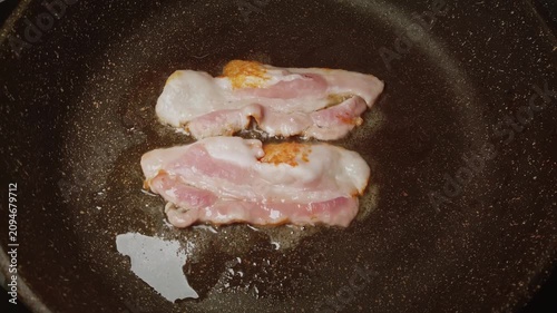 Bacon Sizzling in Skillet: Strips of Uncooked Pork Belly Curling in Hot Oil with Glistening Shape and Browned Edges Overhead Observe